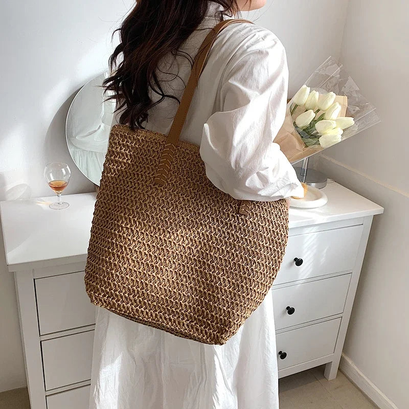 Handwoven summer straw tote bag held on the shoulder
